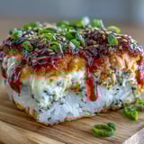 Forkful of layered spicy salmon sushi bake served on a crispy nori chip with avocado.