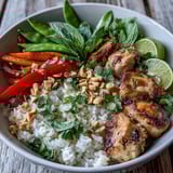 A fresh Thai Chicken Coconut Bowl featuring tender chicken, crunchy snap peas, and aromatic Thai basil, topped with chopped peanuts.