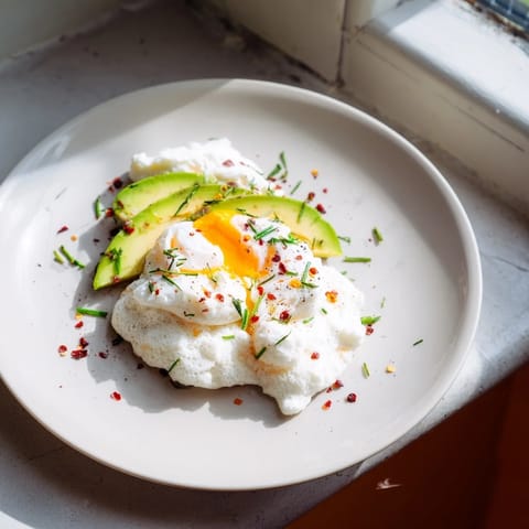 Golden Cloud Bread Breakfast Clouds with runny poached egg yolk dripping onto creamy avocado slices.