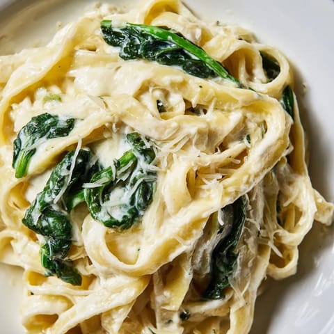 Vibrant wilted spinach and al dente fettuccine coated in a rich, velvety garlic cream sauce.  