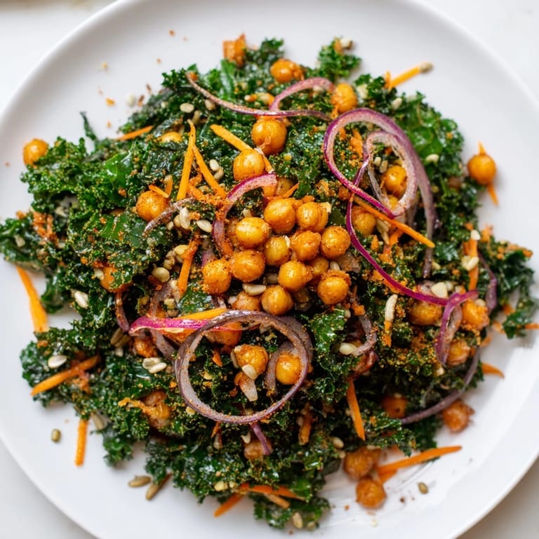 Fresh, chopped kale salad with crunchy roasted chickpeas, carrots, and red onion, ready to eat.