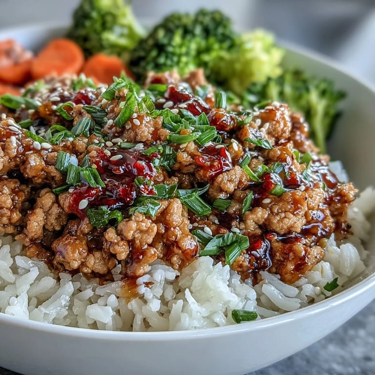 Family-style bowl of Korean-Style Ground Turkey beside chopsticks, fresh chives, and sesame seeds, showcasing a savory, sticky glaze.