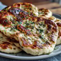 Golden-brown The Best Easy Garlic Naan Bread fresh from a hot cast iron skillet, brushed with garlic butter.